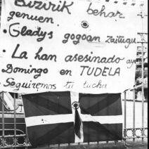 1979ko ekainaren 3an Gladys Del Estal auzotarra, Guardia Zibilak hil zuen Tuteran, martxa antinuklear batean parte hartzen ari zala. Argazkian, Tabakalerako hesietan zintzilikatutako pankarta eta xingoladun ikurriña, Gladysen hilketa salatuz.