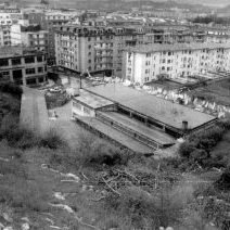 1984. Plaza Handi, Aldakonea gainetik ikusita, bertan, Marmoles Cantabria eta Gomas Lizarribar. 
Urte askotan industria gunea izan zen. Marmoles Cantabria eta Gomas Lizarribar lantegiak ikusten dira, biak argazkiaren datan jada abandonatuak. Urtetan auzotarrak gune horretan auzoarentzako ekipamenduak jar zitzaten borrakatu zuten. Azkenean, kiroldegia, frontoia eta gaur egun Plaza Haundi dena lortu zituzten.