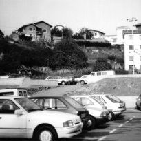 Aparkalekua kotxez beteta.

Auzoan Plaza Haundi aldarrikapen bat izan da. Aparkaleku izan aurretik orube horretan lantegi batzuk zeuden: Marmoles Cantabria, Fábrica de Gomas Lizarribar... Lantegiak desagertu ostean urte luzez orubea ikutu gabe geratu zen.
1987an, Udalak lur saila berdindu zuen eta auzokideen eskakizuna kontutan hartu gabe aparkaleku bat sortu zuen. Mugimendu handia eta ekimen ugari egon ziren aparkaleku horren aurka.